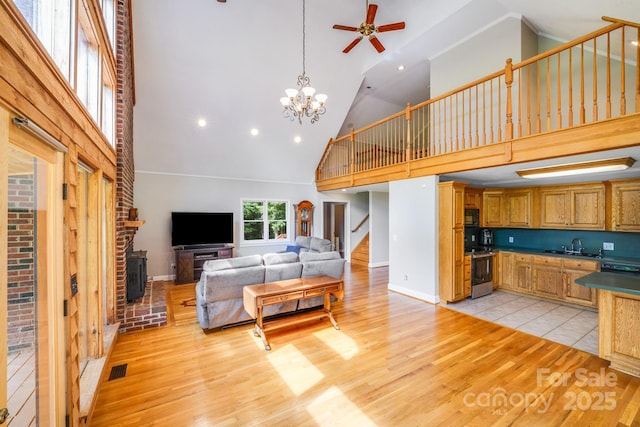 6350 Mount Pleasant Rd S, Concord, NC 28025 - living room with high vaulted ceiling, stairs, light wood-type flooring, a ceiling fan, and a chandelier