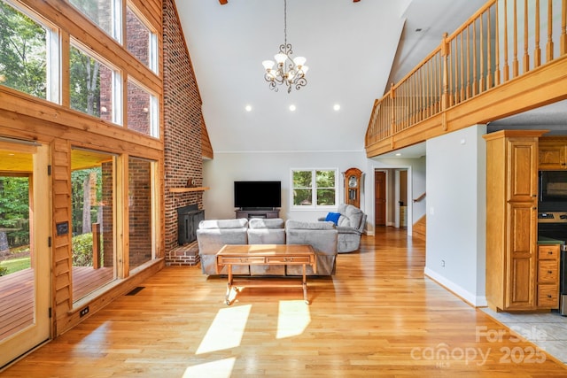 6350 Mount Pleasant Rd S, Concord, NC 28025 - living area with high vaulted ceiling, a chandelier, light wood-style floors, a fireplace, and baseboards