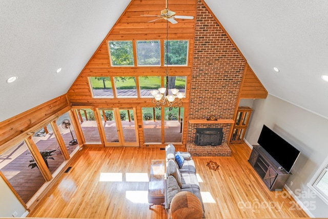 6350 Mount Pleasant Rd S, Concord, NC 28025 - unfurnished living room with high vaulted ceiling, a ceiling fan, wood finished floors, a brick fireplace, and a chandelier