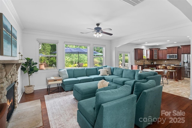 4500 Carrington Dr, Lancaster, SC 29720 - living room featuring crown molding, ceiling fan, a stone fireplace, arched walkways, and baseboards
