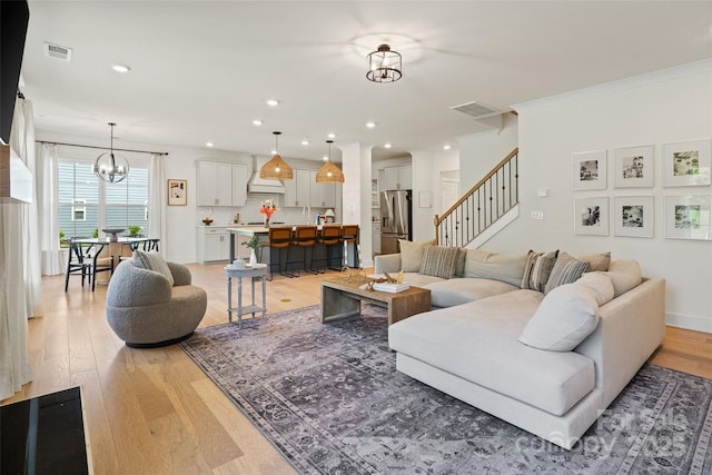 433 Sinaloa St, Waxhaw, NC 28173 - living room with light wood-style floors, stairs, a chandelier, recessed lighting, and ornamental molding
