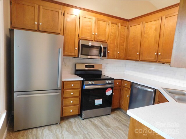 3001 Austin Chaney Rd, Monroe, NC 28110 - kitchen featuring stainless steel appliances, light countertops, tasteful backsplash, brown cabinetry, and a sink