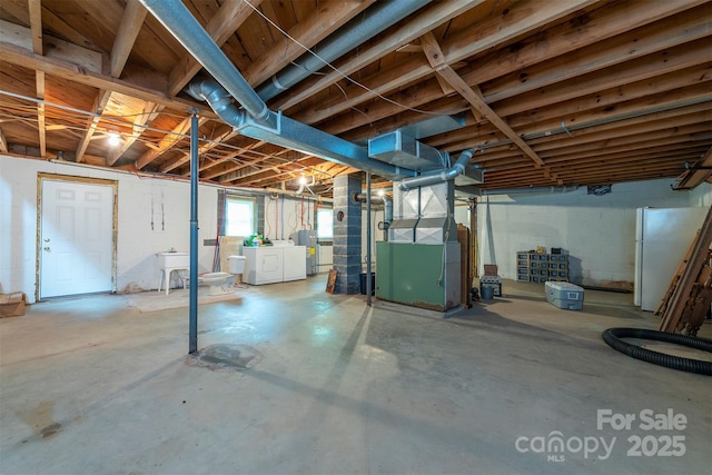 1788 Blue Rock Rd, Burnsville, NC 28714 - basement featuring separate washer and dryer, freestanding refrigerator, heating unit, and concrete block wall