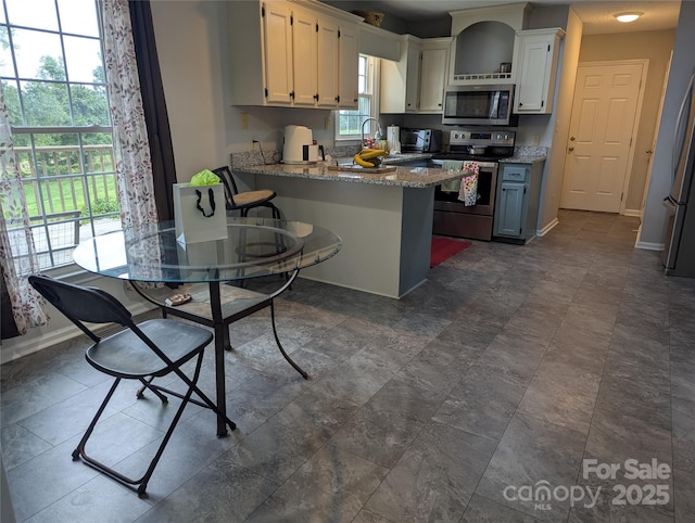 936 New Camp Creek Church Rd Unit 11, Kings Mountain, NC 28086 - kitchen featuring stainless steel appliances, a peninsula, white cabinetry, light stone counters, and baseboards