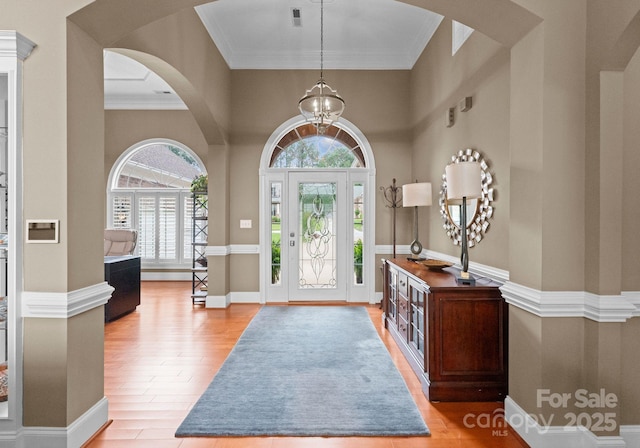 7412 Sahalee Dr, Denver, NC 28037 - foyer entrance with arched walkways, a chandelier, light wood-style flooring, ornamental molding, and a high ceiling