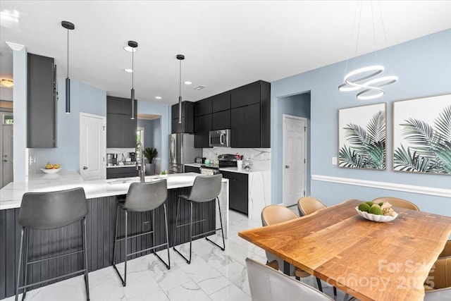 2213 Iron Works Dr, Clover, SC 29710 - kitchen with stainless steel appliances, dark cabinetry, light marble finish flooring, light countertops, and a peninsula