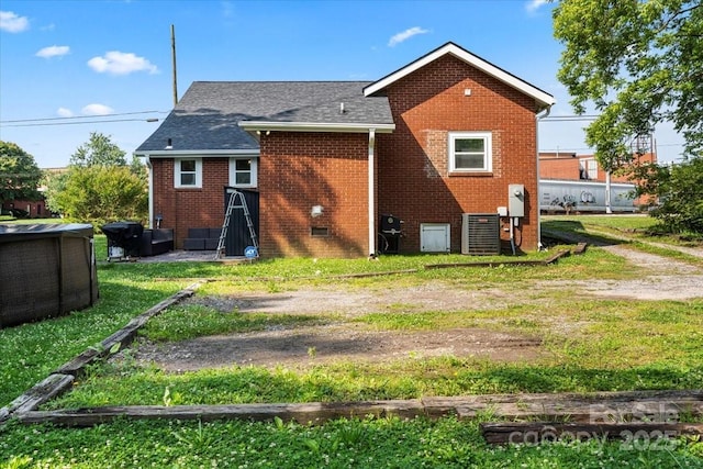 85 Ruritan Park Rd, Stony Point, NC 28678 - rear view of house with brick siding, a shingled roof, a lawn, and central AC unit
