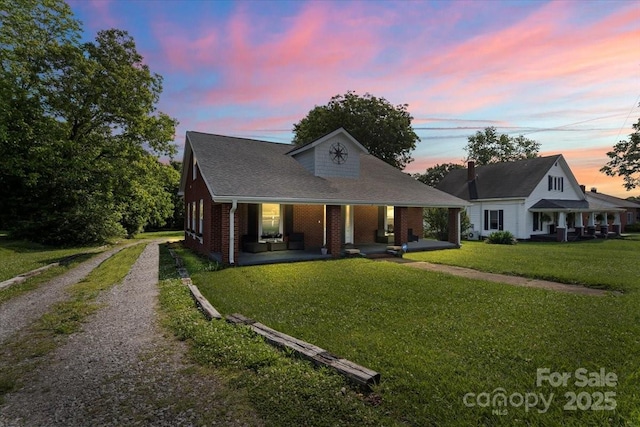 85 Ruritan Park Rd, Stony Point, NC 28678 - view of front of home with covered porch, driveway, a yard, brick siding, and a shingled roof