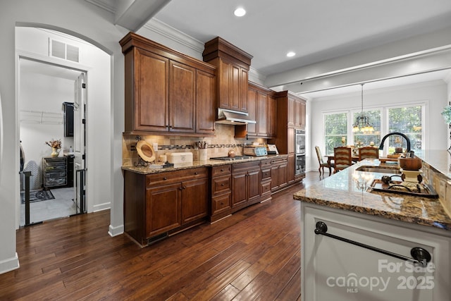 3009 Botetourt Ct, Weddington, NC 28104 - kitchen featuring dark wood-style flooring, decorative backsplash, under cabinet range hood, light stone countertops, and ornamental molding