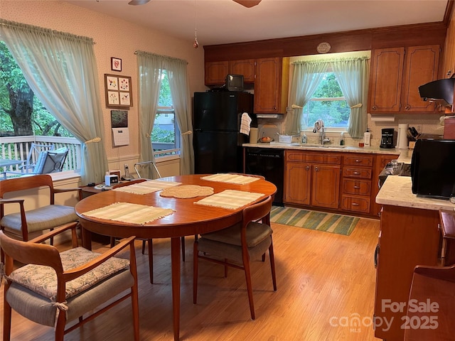 5806 Whitingham Dr, Charlotte, NC 28215 - kitchen with black appliances, a sink, light countertops, brown cabinetry, and under cabinet range hood