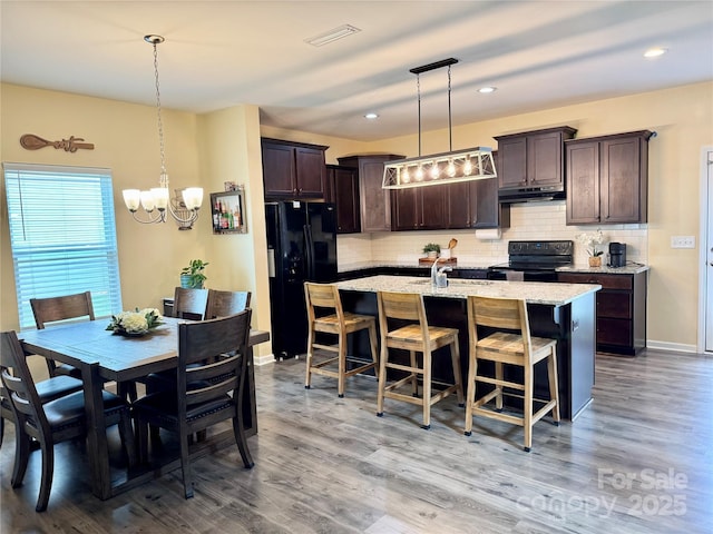 750 Fraternity Row, Kannapolis, NC 28081 - kitchen with black appliances, under cabinet range hood, dark brown cabinets, a chandelier, and tasteful backsplash