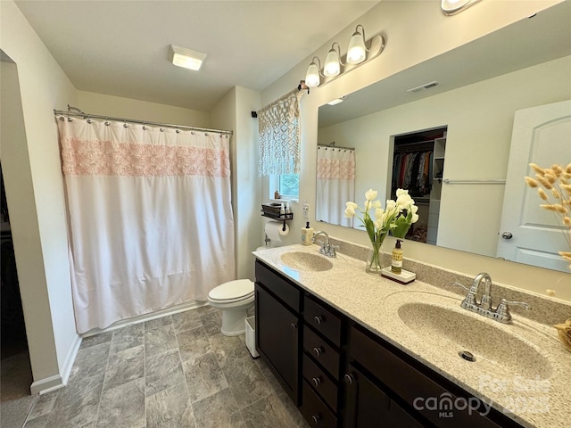 750 Fraternity Row, Kannapolis, NC 28081 - bathroom featuring double vanity, stone finish floors, toilet, curtained shower, and baseboards