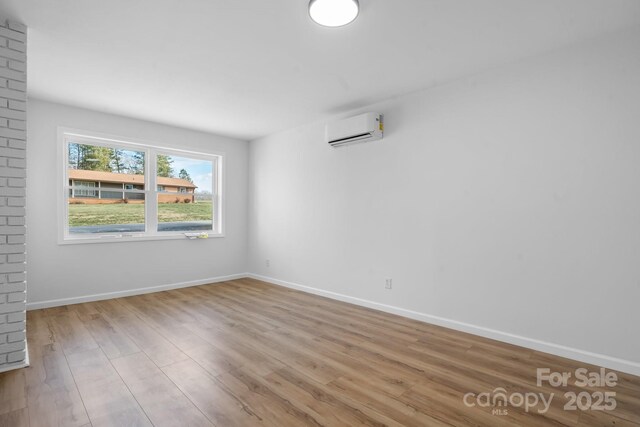5520 Chestnut Dr, Hickory, NC 28602 - empty room featuring an AC wall unit, wood finished floors, and baseboards