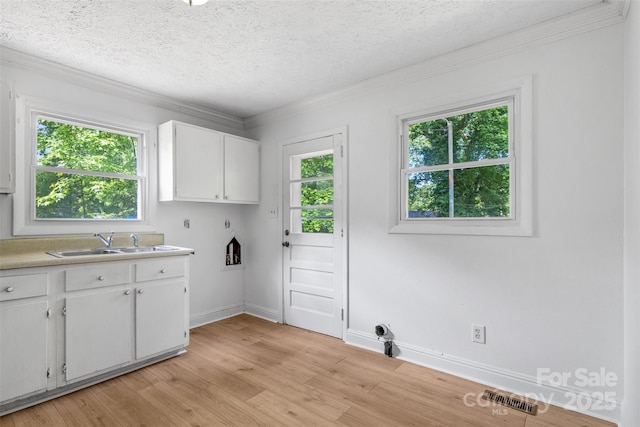 1310 Caldwell St, Greensboro, NC 27406 - laundry room with cabinet space, healthy amount of natural light, a textured ceiling, light wood-style flooring, and baseboards