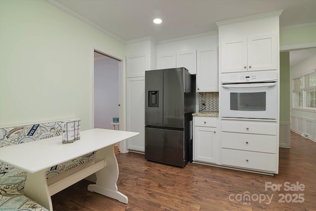 2618 Pineview Dr, Lancaster, SC 29720 - kitchen with stainless steel fridge with ice dispenser, white oven, backsplash, white cabinetry, and ornamental molding
