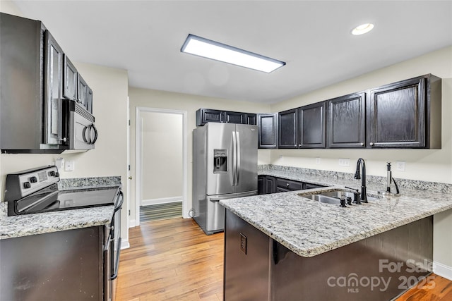 2005 Schofield Pl, Salisbury, NC 28144 - kitchen with appliances with stainless steel finishes, a sink, a peninsula, light wood-style flooring, and light stone countertops