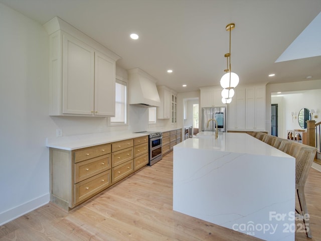 8039 Mcconnell Rd, Denver, NC 28037 - kitchen with appliances with stainless steel finishes, custom range hood, light wood-style floors, a sink, and a center island with sink