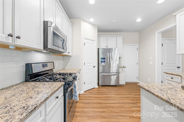 4848 Fonthill Ln, Charlotte, NC 28210 - kitchen with appliances with stainless steel finishes, light wood-style floors, recessed lighting, white cabinets, and decorative backsplash