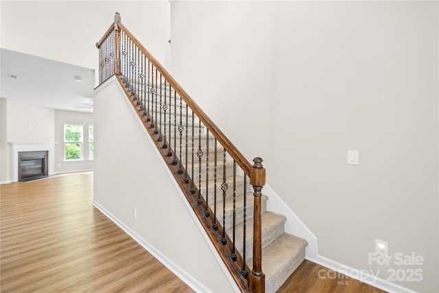 4848 Fonthill Ln, Charlotte, NC 28210 - stairway featuring wood finished floors, a glass covered fireplace, and baseboards