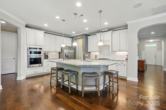3808 Halcyon Dr, Huntersville, NC 28078 - kitchen featuring stainless steel appliances, crown molding, a sink, arched walkways, and dark wood finished floors