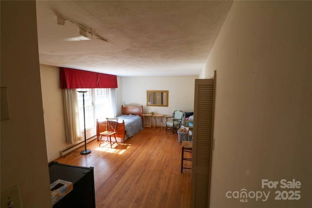 170 Heritage Ln, Salisbury, NC 28147 - bedroom featuring a baseboard radiator, wood finished floors, and a textured ceiling