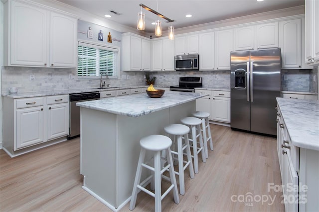 6914 Evanton Loch Rd, Charlotte, NC 28278 - kitchen with stainless steel appliances, a sink, white cabinetry, a breakfast bar area, and ornamental molding