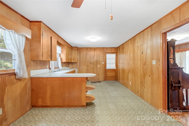 208 Lipe Rd, Troutman, NC 28166 - kitchen featuring wood walls, light countertops, plenty of natural light, brown cabinetry, and a peninsula