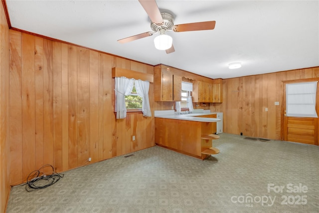 208 Lipe Rd, Troutman, NC 28166 - kitchen with ceiling fan, wood walls, brown cabinetry, a peninsula, and light countertops