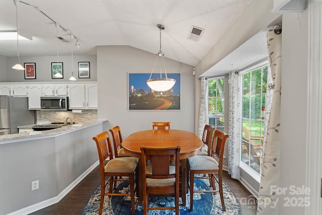 1310 Bellhook Pl NW, Concord, NC 28027 - dining space with dark wood-style floors, vaulted ceiling, rail lighting, and baseboards