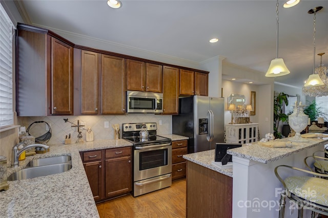 1225 Assembly St, Belmont, NC 28012 - kitchen featuring stainless steel appliances, a sink, a breakfast bar area, light wood finished floors, and tasteful backsplash