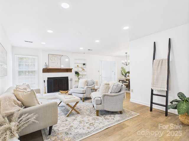 4905 Chestnut Lake Dr, Charlotte, NC 28227 - living room with a chandelier, wood finished floors, a fireplace, recessed lighting, and built in features