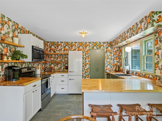 90 W Skyland Cir Unit 1, Asheville, NC 28804 - kitchen featuring butcher block countertops, appliances with stainless steel finishes, wallpapered walls, a sink, and a breakfast bar