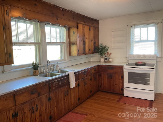 2138 SW Haven Cir, Lenoir, NC 28645 - kitchen featuring white electric range oven, a sink, light wood-style flooring, light countertops, and brown cabinets