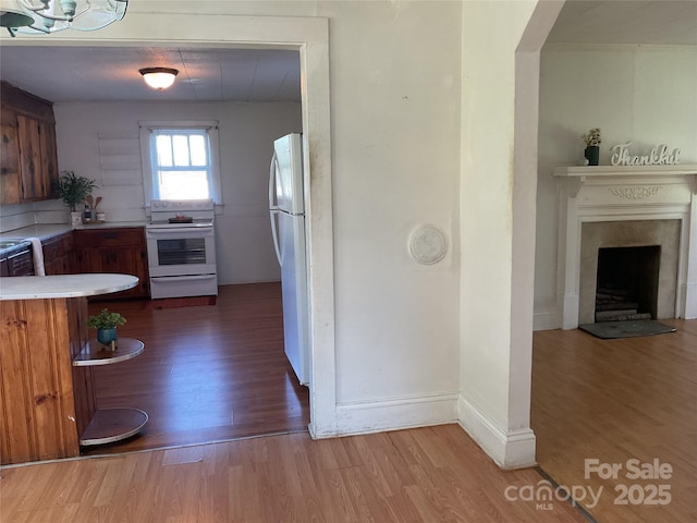 2138 SW Haven Cir, Lenoir, NC 28645 - kitchen featuring white appliances, wood finished floors, brown cabinets, light countertops, and a fireplace