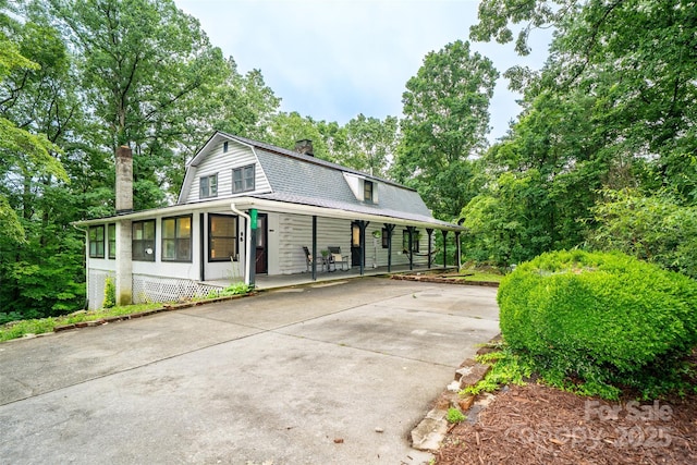 15 Wilson Way, Flat Rock, NC 28731 - view of front of home featuring a chimney, covered porch, concrete driveway, a gambrel roof, and view of wooded area