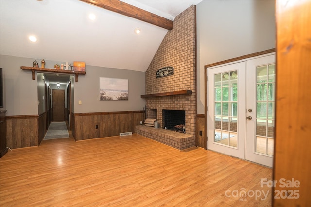 1565 Earnhardt Rd, Salisbury, NC 28146 - unfurnished living room featuring light wood-style floors, beam ceiling, a wainscoted wall, french doors, and a brick fireplace