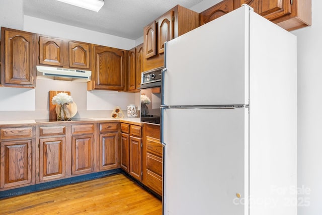 220 W Park Dr, Morganton, NC 28655 - kitchen with black appliances, under cabinet range hood, brown cabinets, and light wood-type flooring