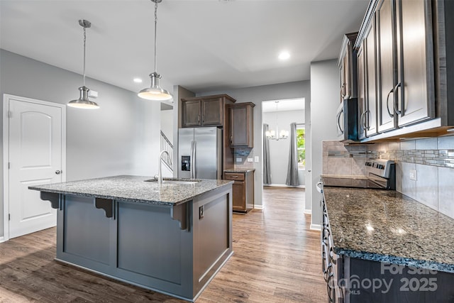 3053 Riker St, Clover, SC 29710 - kitchen with appliances with stainless steel finishes, a sink, decorative backsplash, wood finished floors, and a kitchen bar