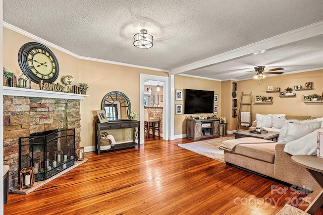 454 N Eastway Dr, Troutman, NC 28166 - living area with a textured ceiling, hardwood / wood-style flooring, a stone fireplace, crown molding, and a ceiling fan