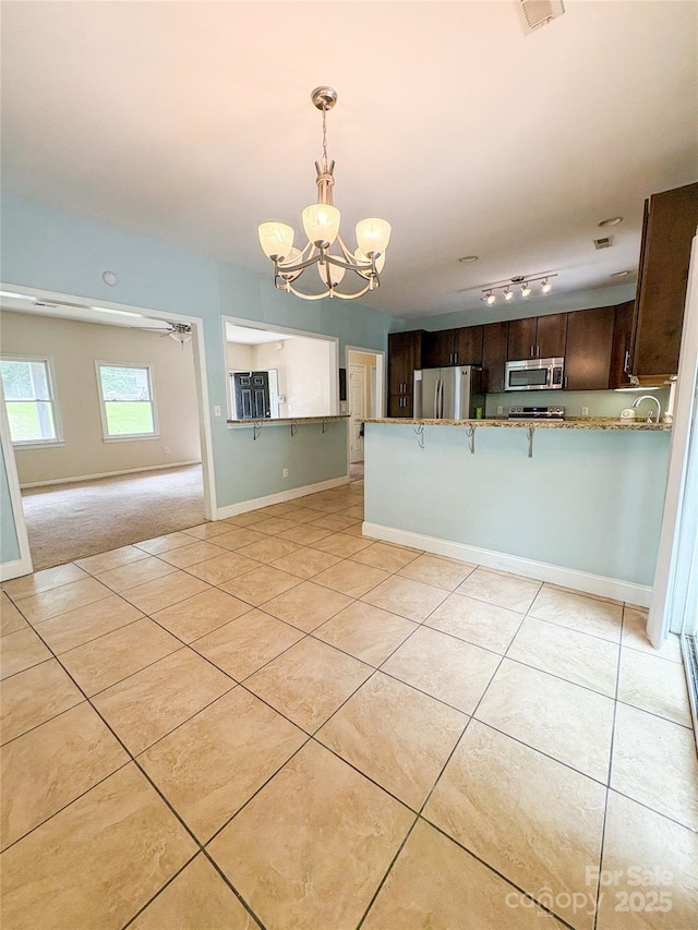 3430 Fincher Blvd, Charlotte, NC 28269 - kitchen with appliances with stainless steel finishes, a chandelier, dark brown cabinetry, and light tile patterned floors