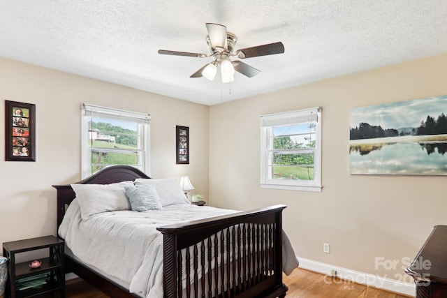 68 Broyles Rd, Hendersonville, NC 28791 - bedroom featuring multiple windows, wood finished floors, baseboards, ceiling fan, and a textured ceiling