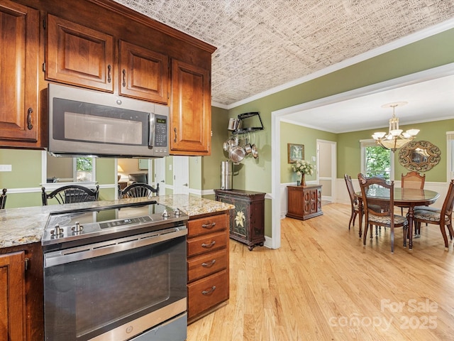 10710 Bristlecone Ct, Mint Hill, NC 28227 - kitchen featuring appliances with stainless steel finishes, ornamental molding, light wood-type flooring, a chandelier, and light stone countertops