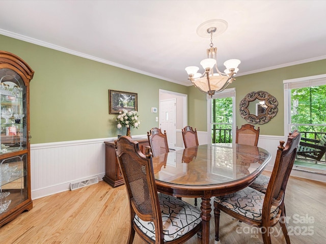 10710 Bristlecone Ct, Mint Hill, NC 28227 - dining space featuring a chandelier, light wood-style floors, wainscoting, and crown molding