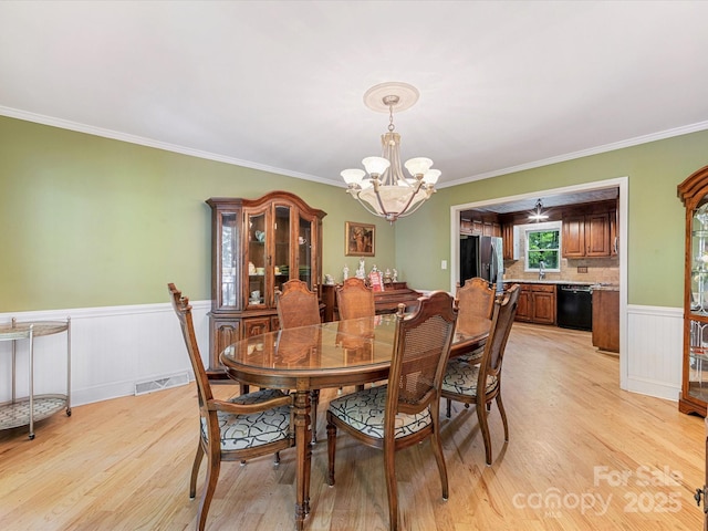 10710 Bristlecone Ct, Mint Hill, NC 28227 - dining area featuring a chandelier, light wood finished floors, crown molding, and a wainscoted wall