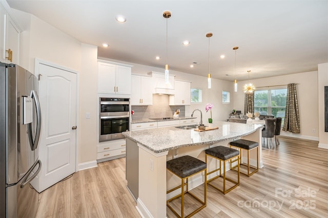 705 Hinterland Ln, Matthews, NC 28104 - kitchen with appliances with stainless steel finishes, a sink, light wood-style flooring, a breakfast bar, and white cabinets