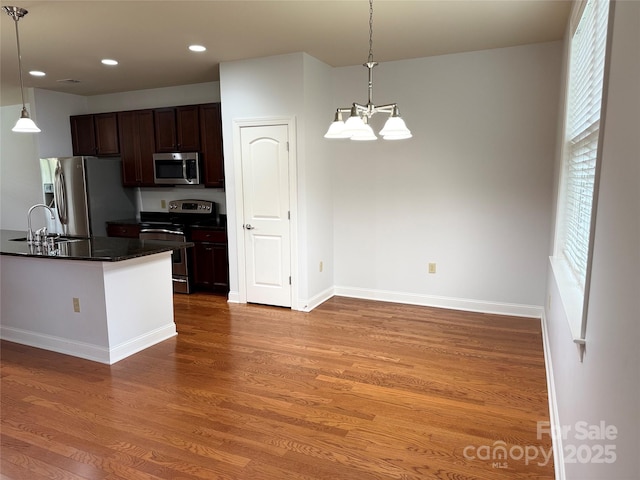 129 Steinbeck Way Unit B, Mooresville, NC 28117 - kitchen featuring appliances with stainless steel finishes, dark countertops, a sink, wood finished floors, and hanging light fixtures