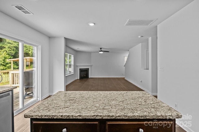 2021 Tarzi Ln, Charlotte, NC 28215 - kitchen with wood finished floors, ceiling fan, light stone counters, dark brown cabinetry, and a kitchen island