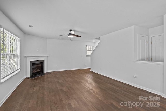 2021 Tarzi Ln, Charlotte, NC 28215 - unfurnished living room with dark wood-style flooring, healthy amount of natural light, a ceiling fan, and a glass covered fireplace