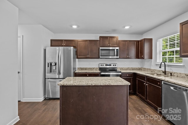 2021 Tarzi Ln, Charlotte, NC 28215 - kitchen featuring appliances with stainless steel finishes, dark wood-style floors, a kitchen island, dark brown cabinetry, and light stone counters
