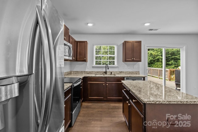 2021 Tarzi Ln, Charlotte, NC 28215 - kitchen featuring stainless steel appliances, dark wood-style floors, a center island, light stone counters, and dark brown cabinetry